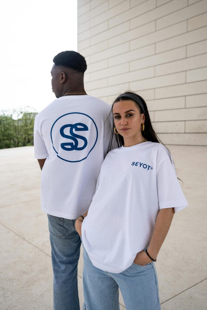 Two stylish individuals in white t-shirts pose outdoors in Bordeaux, France. Modern urban fashion.