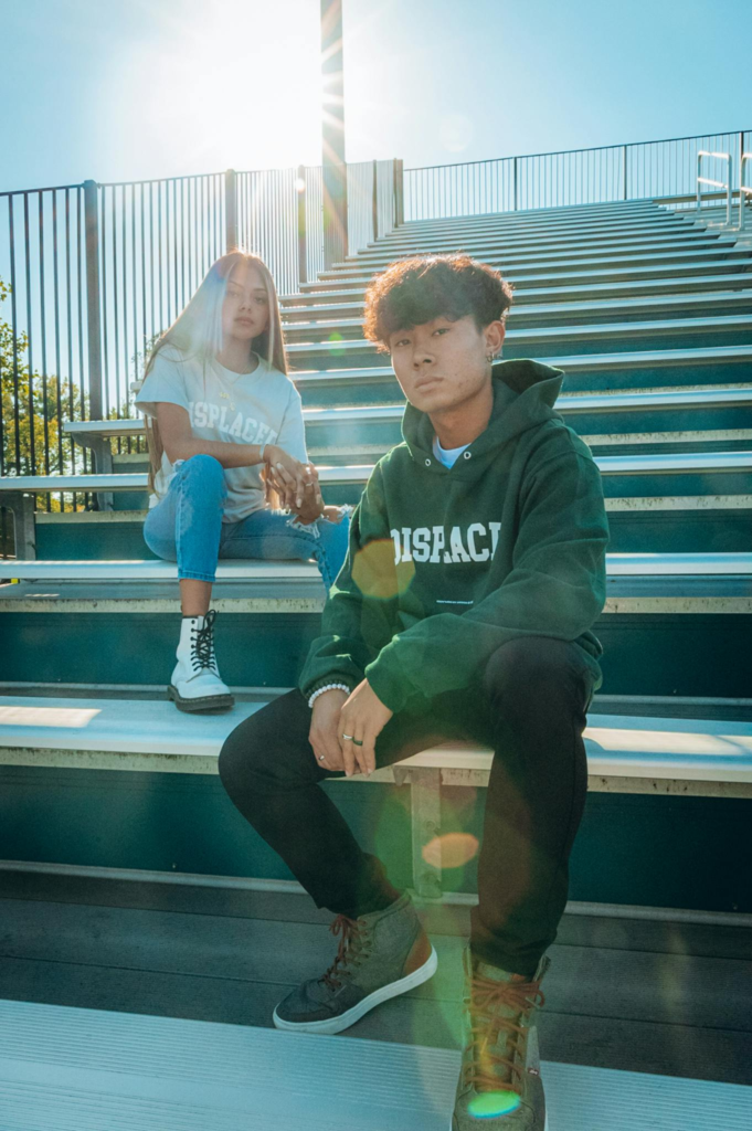 Young adults in casual wear sitting on bleachers in sunlight, urban setting.